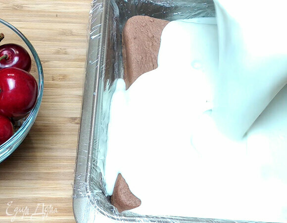 Помещаем шоколадный бисквит в форму и заливаем молочной смесью, украшаем ягодами красной смородины. Ставим остывать.