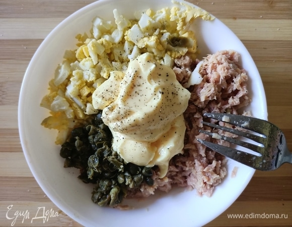 Яйца мелко нарежьте. С тунца слейте жидкость, измельчите с помощью вилки. Добавьте мелко нарезанные каперсы, майонез и черный молотый перец. Аккуратно все перемешайте.