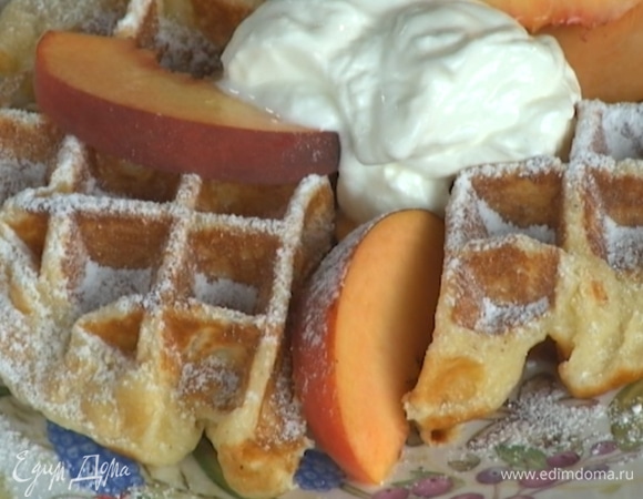 Готовые вафли подавать с персиками, присыпав сахарной пудрой и украсив йогуртом.