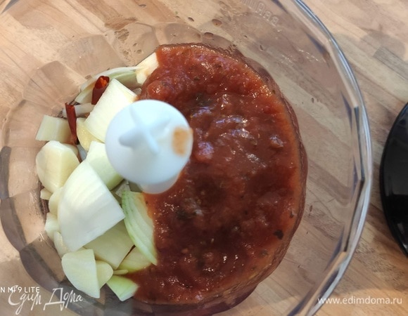 В блендер отправить половину луковицы, чеснок, перец чили (количество регулируйте по своему вкусу) и томаты в собственном соку вместе с соком. Перебить мелко, но так, чтобы осталась какая-то текстура.