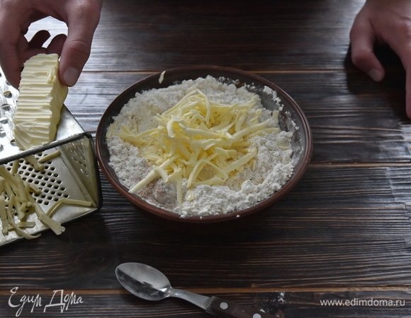 Сливочное масло достать из морозильной камеры и натереть на терке. Добавить к сухим ингредиентам.