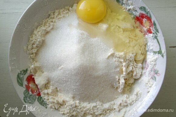 В мучную крошку добавить яйцо и сахар, перемешать до однородности и замесить тесто.