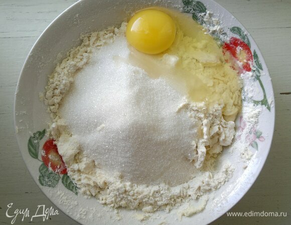В мучную крошку добавить яйцо и сахар, перемешать до однородности и замесить тесто.
