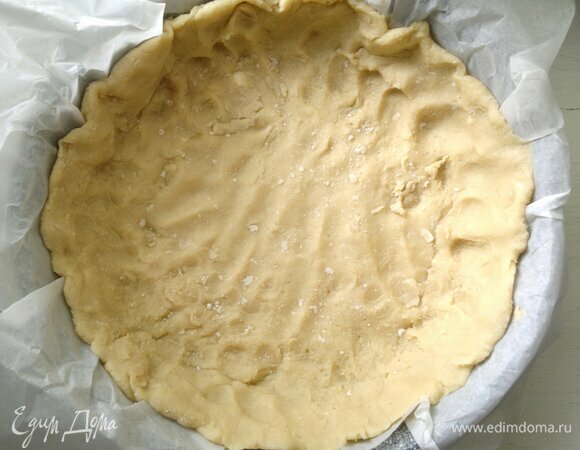 Форму для запекания застелить бумагой для выпечки. Распределить тесто по дну и бокам формы. У меня форма диаметром 24 см.