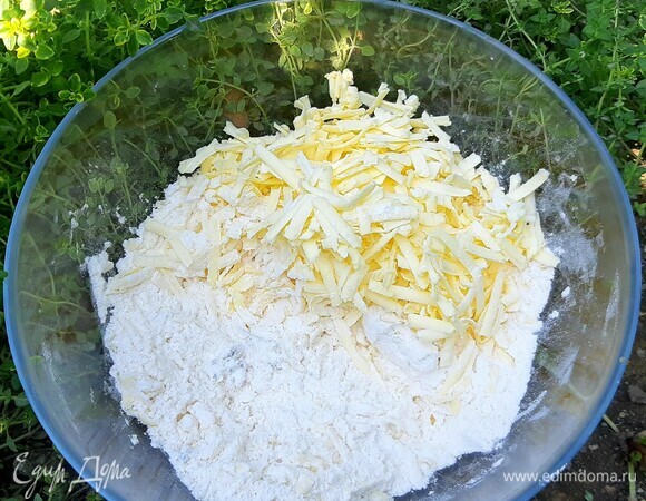 Первым делом приготовить тесто. В миску всыпать муку, обвалять в ней ледяное сливочное масло и натереть на терке в ту же муку. Так масло не будет таять и прилипать к терке. Добавить четверть чайной ложки разрыхлителя, соль, 30 мл холодной воды, также измельченный свежий тимьян.