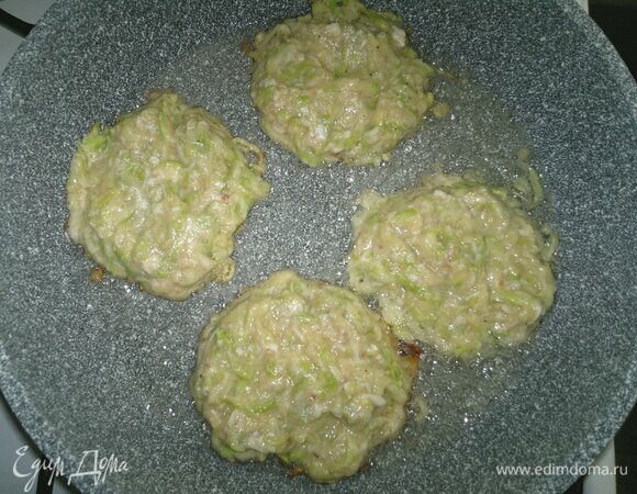 В сковороду налить часть масла, выложить ложкой кабачковое тесто в форме круглых или овальных оладий. Поджарить до румяности с одной стороны.