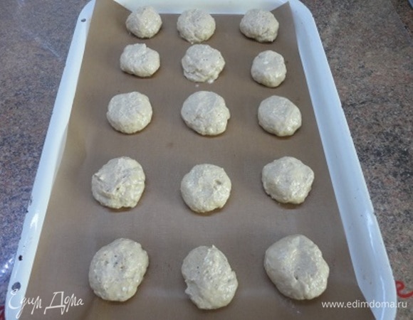 Духовку нагреть до 190–200°C. Из теста сформировать шарики смоченными в воде руками величиной с грецкий орех. Выложить их на противень и слегка приплюснуть пальцем.