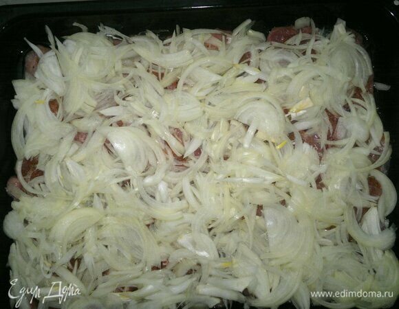 Выложить слой лука на свинину.
