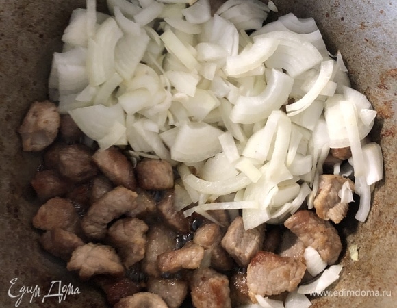 К румяному мясу добавьте лук.