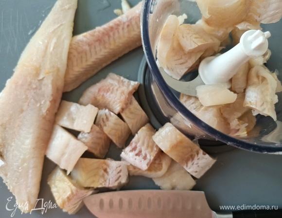 Рыбное филе нарезать на небольшие кусочки, переложить в чашу блендера, туда же добавить лук и измельчить до состояния пюре.