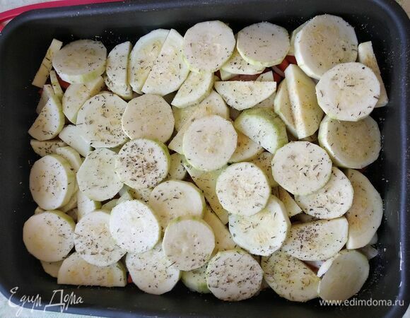 Сверху выложить кабачки, посолить, поперчить и посыпать сухими травами.