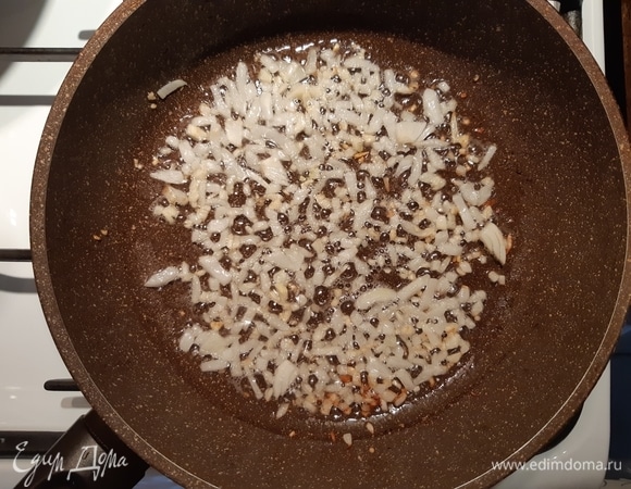 Наливаем растительное масло на сковороду, кладем лук и чеснок, обжариваем до золотистого цвета.