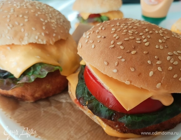 Начинаем собирать наш фишбургер: берем булочку для бургеров, разрезаем пополам и слегка просушиваем обе части со стороны среза на сковороде без масла. Берем нижнюю часть булочки, поливаем соусом и начинаем выкладывать сыр, рыбную котлету, лист салата, помидор, снова сыр, поливаем небольшим количеством соуса. Сверху бургер накрываем верхней частью булочки с кунжутом. Морской фишбургер готов. Подавать его желательно теплым. Приятного аппетита!