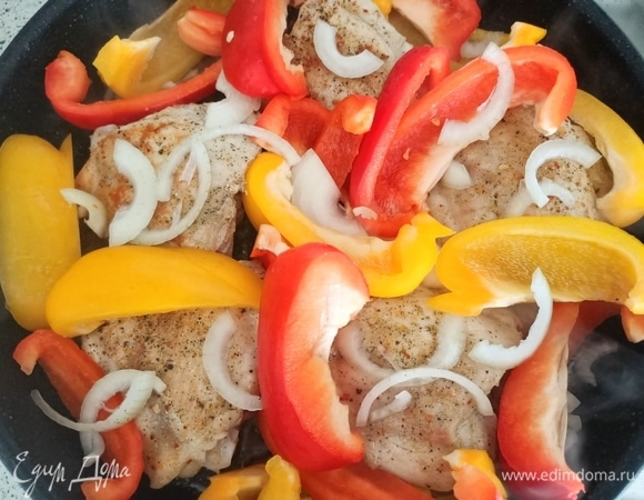 Сверху на мясо выкладываем лук и болгарский перец. Накрываем крышкой и тушим 5 минут.