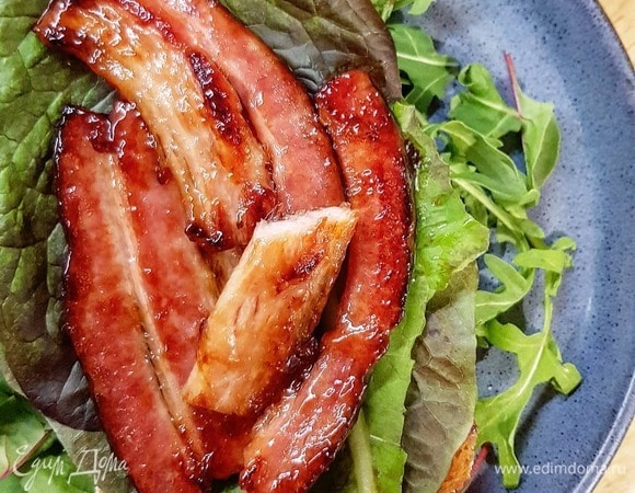 Соберите сэндвич: хлеб, салат, грудинка, слайсы томата, ложка соуса и снова хлеб.