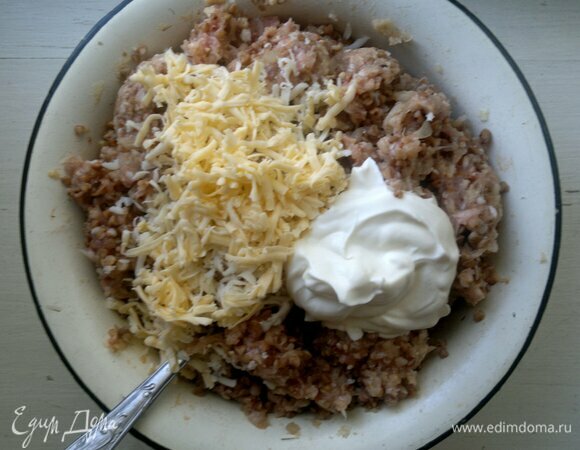 В фарш добавить сметану и половину натертого сыра, перемешать.