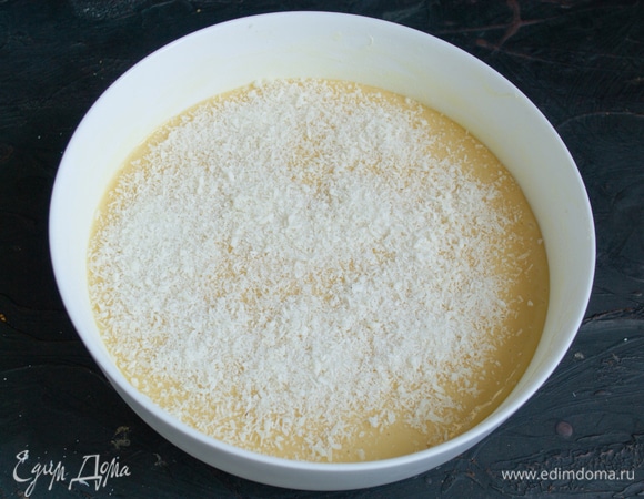 Выливаем тесто в форму. Смешиваем кокосовую стружку с оставшимся сахаром, посыпаем тесто.