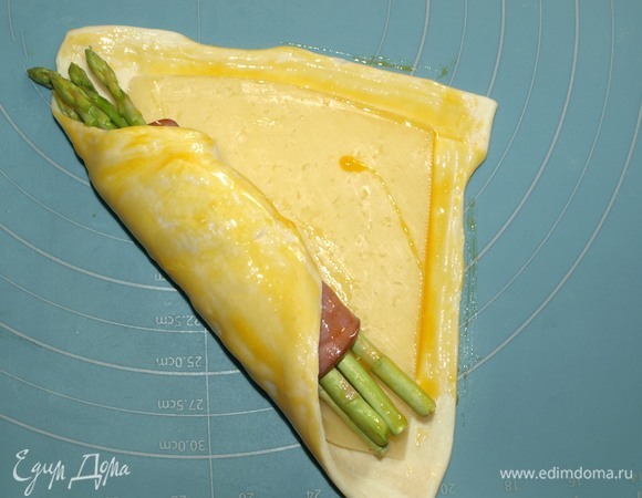Куриный желток взболтать. Один угол теста завернуть, смазать желтком, внахлест завернуть второй угол.