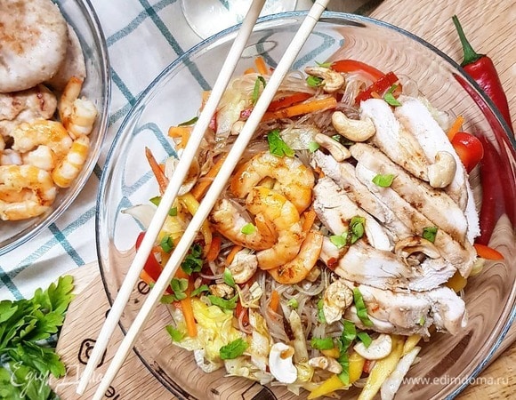 Смешиваем нашу фунчозу с нарезанными овощами и манго, вливаем приготовленный соус. Выкладываем на большое блюдо фунчозу с овощами. Грудку нарезаем слайсами. Поверх лапши выкладываем грудку, креветки, посыпаем все кешью. Выливаем сверху остатки соуса, даем свежей петрушки, если нужно.