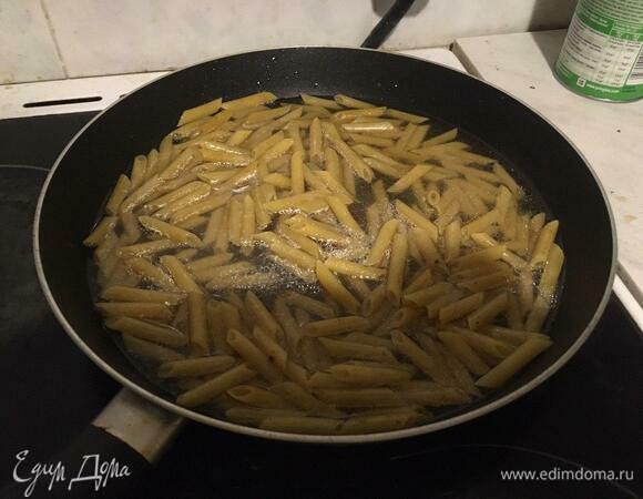 В сковороду наливаем масло для жарки и высыпаем в нее сырые макароны так, чтобы закрывало дно сковороды. Перемешиваем лопаткой макароны, чтобы они были полностью в масле — так они не слипнутся при варке. Включаем плиту на средний огонь, заливаем макароны холодной водой, чтобы их слегка покрыло, закрываем крышкой. Варим примерно 10 минут, периодически помешивая, до исчезновения большей части воды. Если данный вариант кажется вам сложным, отварите макароны отдельно в кастрюле до полуготовности и переложите на сковороду с маслом уже в отваренном виде.