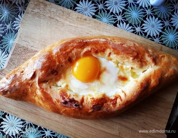 Когда хачапури будет готово, достаем из духовки, смазываем все сливочным маслом, кусочек сливочного масла добавляем внутрь к сыру и выливаем желток в середину. Ставим в духовку на 2 минуты. Вуаля — все готово, можно трапезничать!