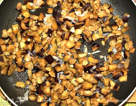 В сковороде разогреть растительное масло. Добавить чеснок и лук. Готовить до прозрачности лука. Добавить промытые и отжатые баклажаны, готовить 5–7 минут.