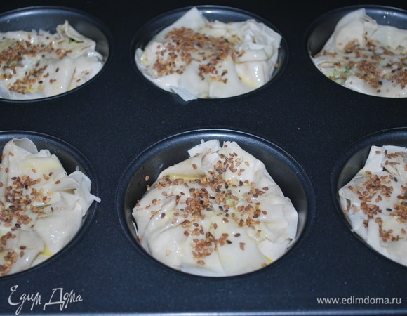 Начинку прикрыть тестом, смазать яйцом и посыпать семенами кунжута. Сверху форму закрыть фольгой (тесто фило очень быстро готовится) и поставить пироги выпекаться в духовку при температуре 170°C на 30 минут.