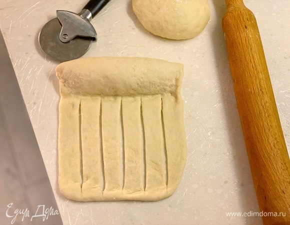 Завернуть и защипнуть со всех сторон. Разрезать второй край теста на полоски, но не до конца.