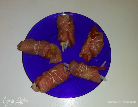 Свернуть кусочки свиной вырезки с овощами в рулетики и обмотать их кулинарной нитью.