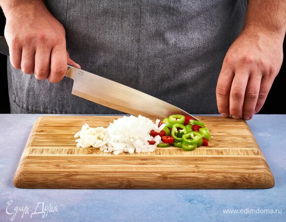 Для начала приготовьте соус чили. Промойте и просушите перцы, разрежьте их пополам и удалите семена. Нарежьте очищенные перцы кольцами, лук мелким кубиком, чеснок слайсами. 