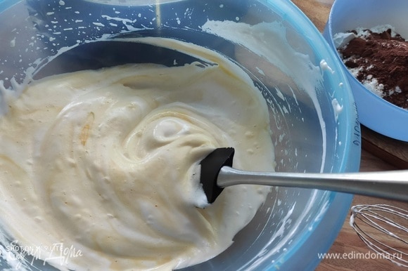 Осторожно добавить яичные желтки, перемешать лопаточкой. Аккуратно вмешать просеянную муку, крахмал и какао. Смешать одну столовую ложку теста с растопленным маслом и вмешать его в тесто.