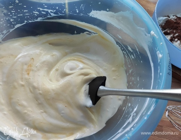 Осторожно добавить яичные желтки, перемешать лопаточкой. Аккуратно вмешать просеянную муку, крахмал и какао. Смешать одну столовую ложку теста с растопленным маслом и вмешать его в тесто.