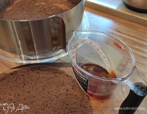 Сборка: на блюдо или подставку нанести тонкий слой шоколада для устойчивости торта. Бисквит разрезать на 2 коржа. Выложить первый корж на блюдо, вокруг него установить кольцо. Пропитать половиной сиропа (цедру удалить).