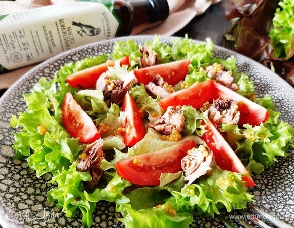 На блюдо выкладываем листья салата, сверху — дольки томата и кусочки тунца. Поливаем заправкой. Подаем салат сразу. Приятного аппетита!