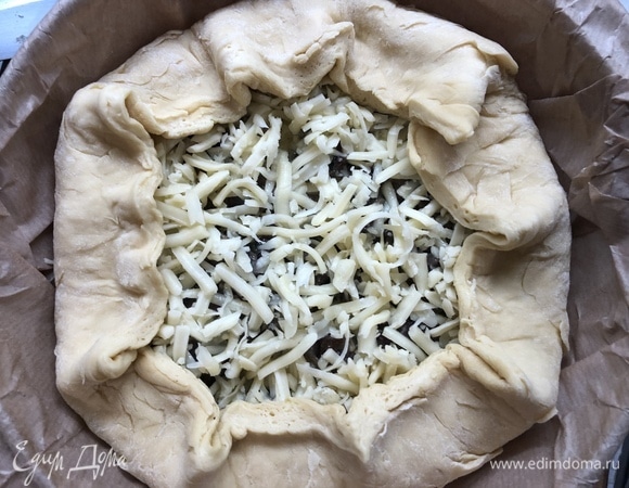 Заливаем заправкой, засыпаем сыром, подворачиваем края, убираем в разогретую до 180°C духовку на 30 минут.