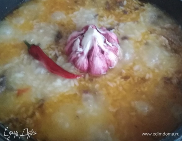 Когда вода на поверхности выпарится до уровня риса, добавить чеснок и острый перец. Влить винный уксус.