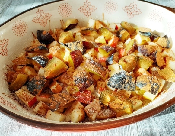 Форму для выпечки смазываем сливочным маслом. Яблоки и сливу нарезаем средним кубиком. Кладем в форму. Посыпаем сахаром и корицей.