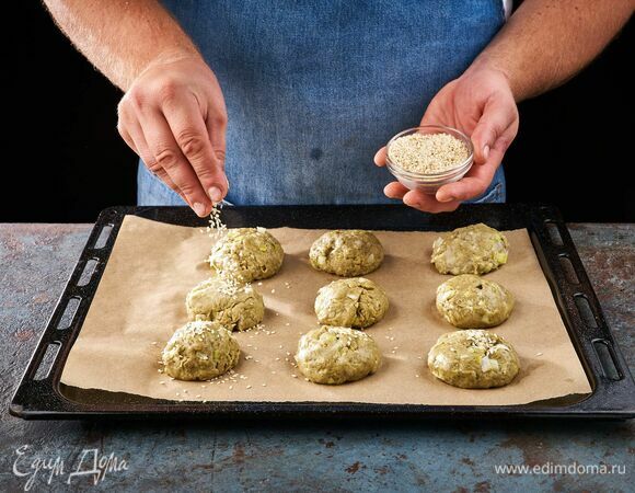 Сформируйте шарики и выложите на противень, застеленный пергаментной бумагой. Сверху шарики посыпьте семечками кунжута. Выпекайте в духовке, разогретой до 180°C, около 30 минут.