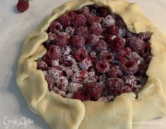 Раскатываем тесто в круг на пергаменте, выкладываем в середину начинку, оставляя с края 2–3 см на загиб. Склеиваем края наискосок, смазываем желтком и посыпаем щепоткой сахара.