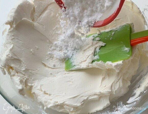 В отдельную посуду частями по 200–300 г выложите холодный творожный или сливочный сыр, каждую часть разминая лопаткой. В конце добавьте 100 г сахарной пудры и снова перемешайте лопаткой, а затем немного взбейте миксером.