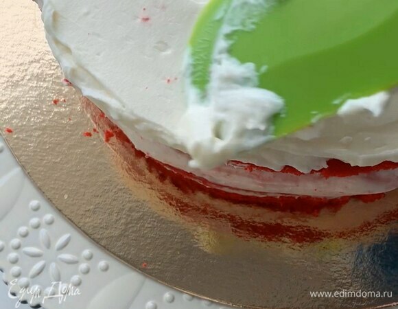 Крем разделите на четыре равные части примерно по 310 г. Три части уйдет на слои и одна часть — на финальное смазывание. Выложите немного крема на блюдо для фиксации первого коржа, затем выкладывайте крем толщиной примерно 7 мм. В конце смажьте торт целиком.