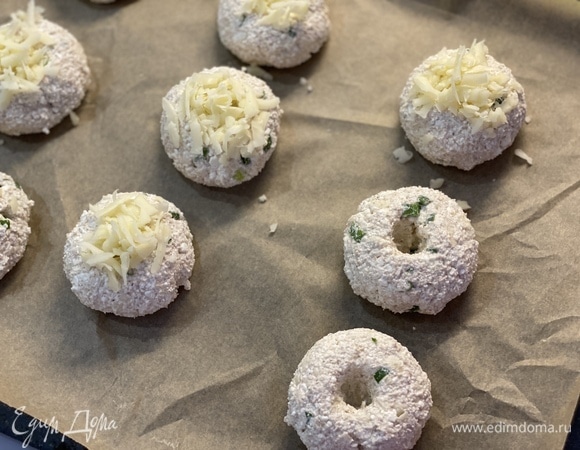 Немного прижать и сделать в центре ямочки. Посыпать тертым сыром.