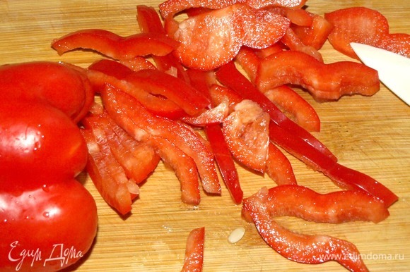 Красный сладкий перец очистить от плодоножки, перегородок и тонко нарезать.
