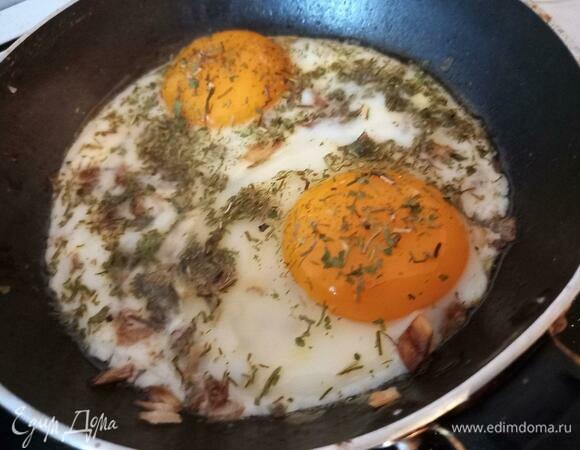 Через 2 минуты снять крышку и пожарить яичницу еще пару минут. При желании не схватившийся белок аккуратно можно распределить по площади другого белка.