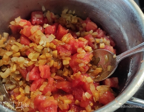В большой кастрюле разогреть оливковое масло и пассеровать лук с чесноком до прозрачности. Добавить смесь специй и жарить до появления стойкого аромата. Затем добавить мелко рубленные помидоры (можно заранее снять с них кожицу). Тушить 10 минут.