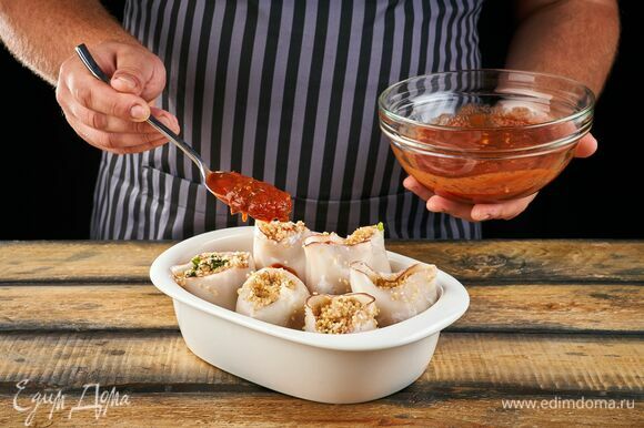 Выложите фаршированных кальмаров в форму для запекания, смазанную маслом. Залейте соусом. Выпекайте в разогретой до 180°C духовке около 25 минут.