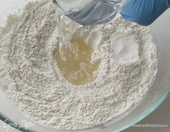 Сделайте небольшое углубление в центре и влейте растительное масло, воду.