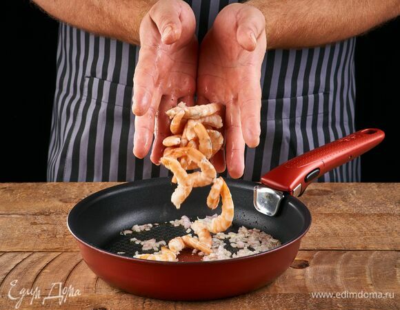 Обжарьте лук на сковороде в небольшом количестве растительного масла. Добавьте очищенные креветки. Обжарьте вместе луком около 2 минут.