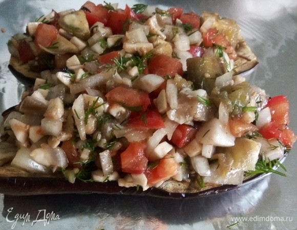 Баклажаны размещаем близко друг к другу и выкладываем всю начинку. Получится большая горка, но она осядет в процессе запекания.