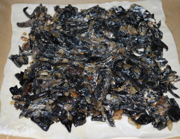 На пласт слоеного теста выложила начинку и сформировала пирог.